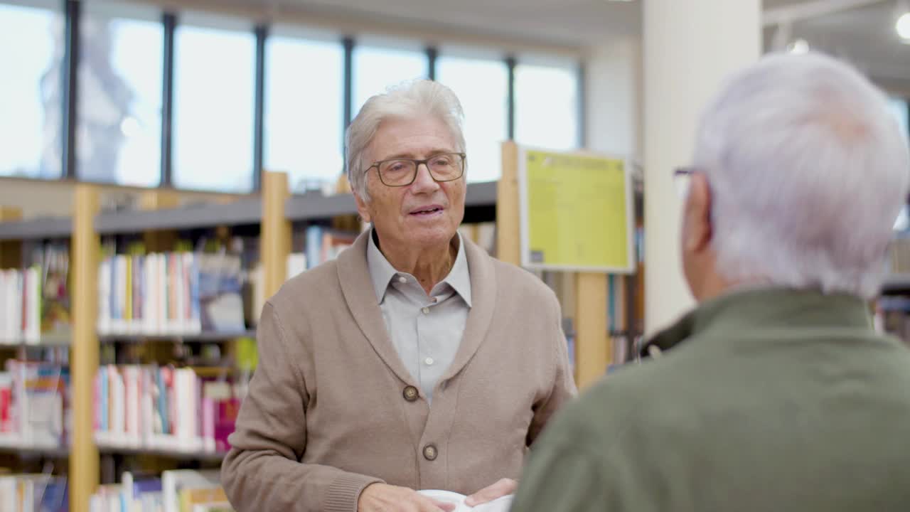 帅气的老男人在图书馆和朋友争论书视频素材