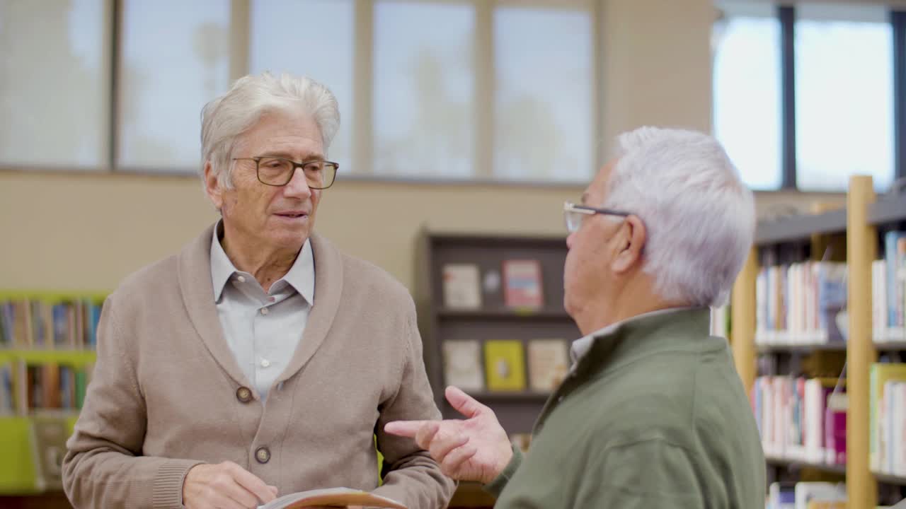 年长的白人男子在图书馆讨论书籍视频素材