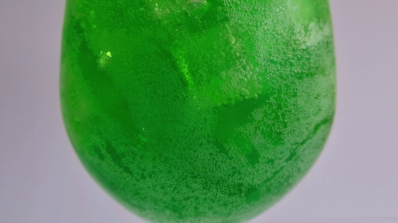 将绿色苏打水倒入盛满冰块的玻璃杯中，这是一杯清凉解渴的饮料。视频下载