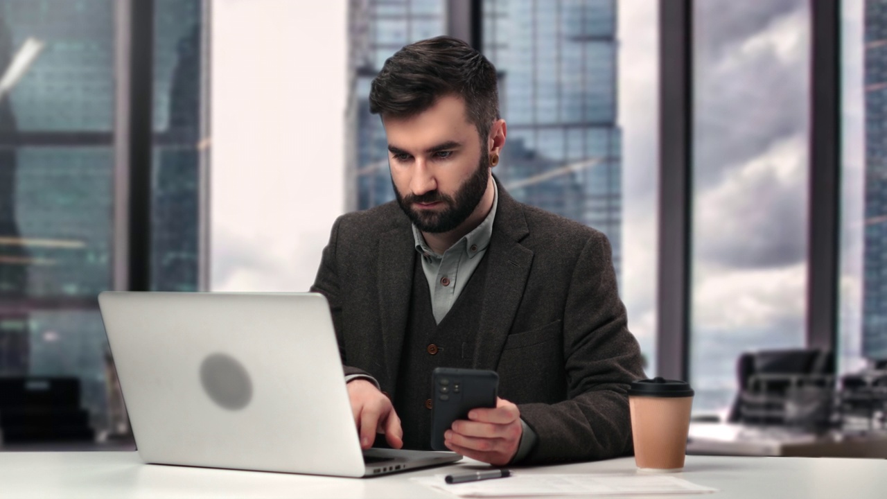 熟练的商业男性经理老板工作使用智能手机笔记本电脑办公桌在现代写字楼视频下载