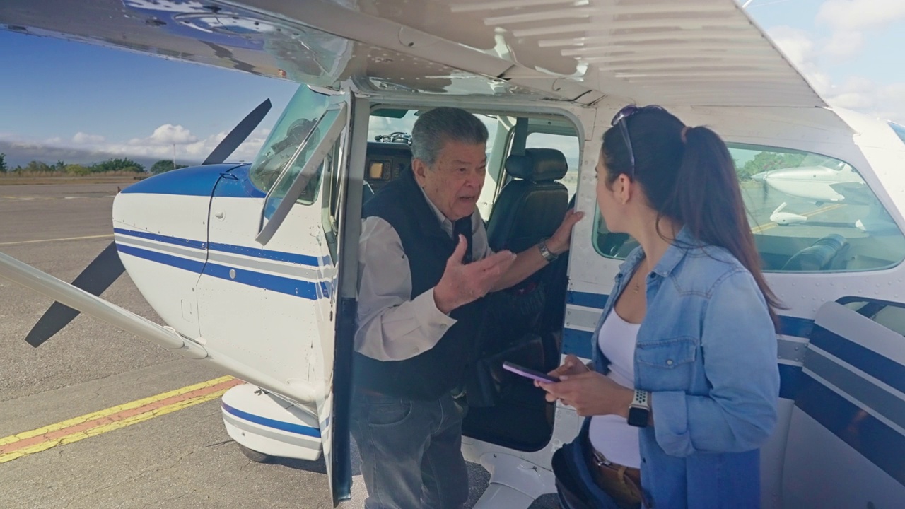 西班牙裔高级飞行员和一名女子在小飞机起飞前在外面交谈视频下载