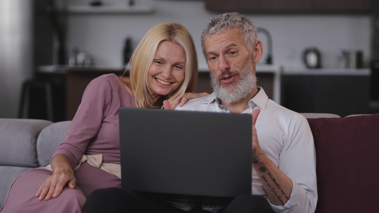 那对快乐的老夫妇在笔记本电脑上聊天。慢动作视频下载