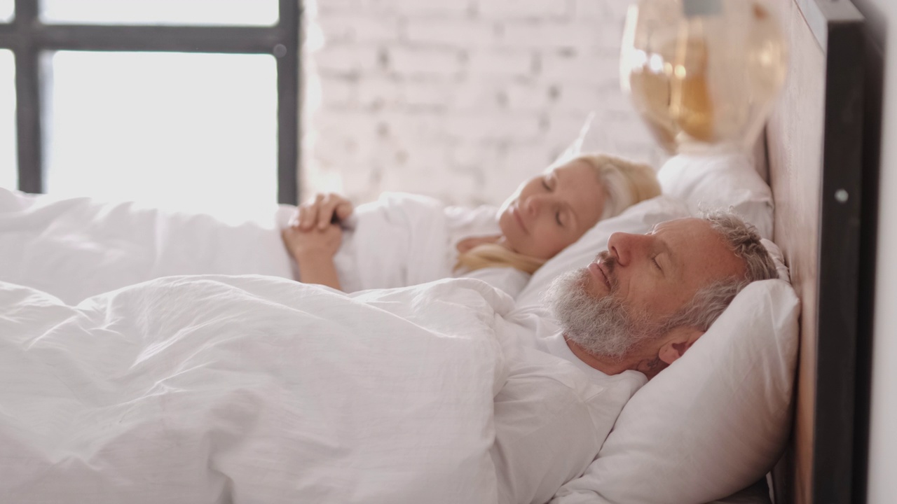 那对中年夫妇睡在床上。慢动作视频下载
