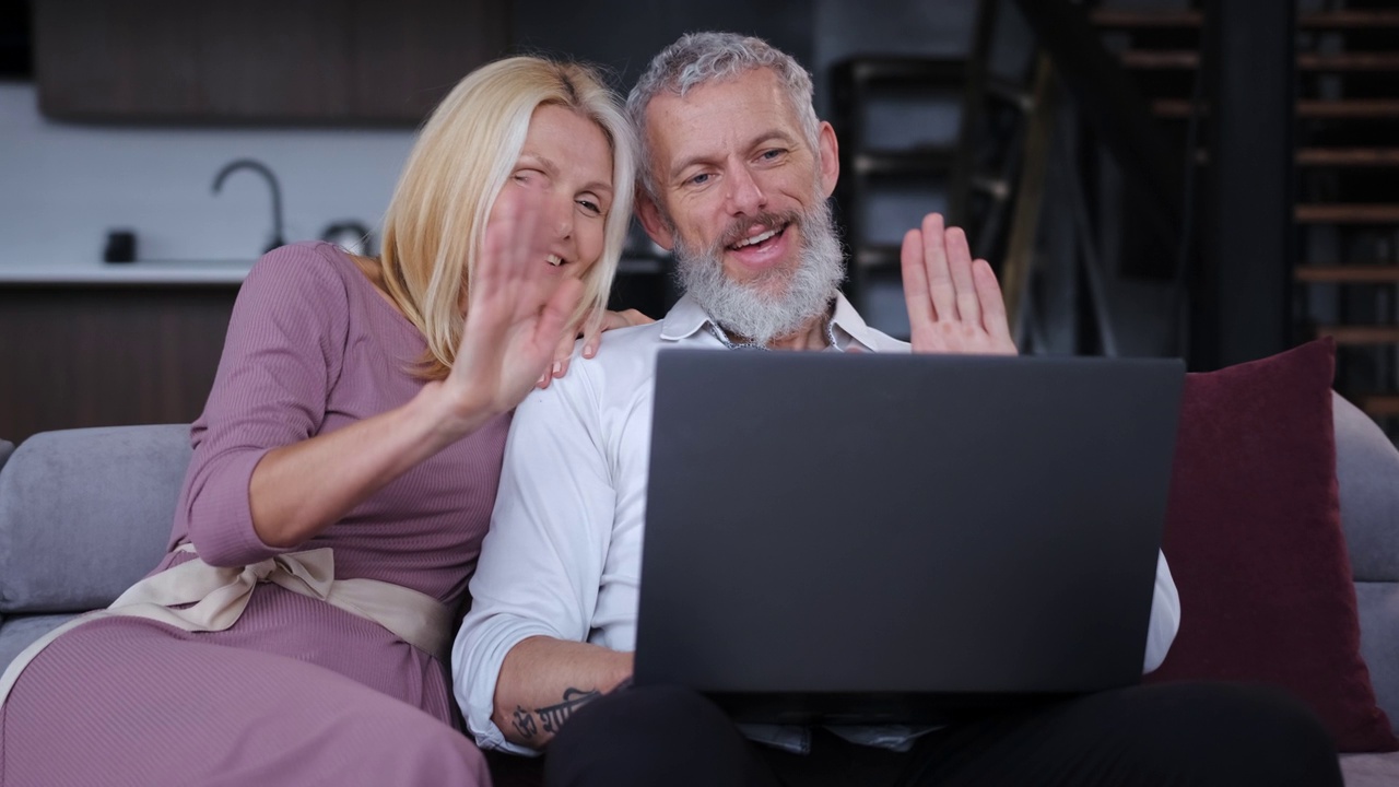 一对幸福的中年夫妇在笔记本电脑上聊天。慢动作视频下载