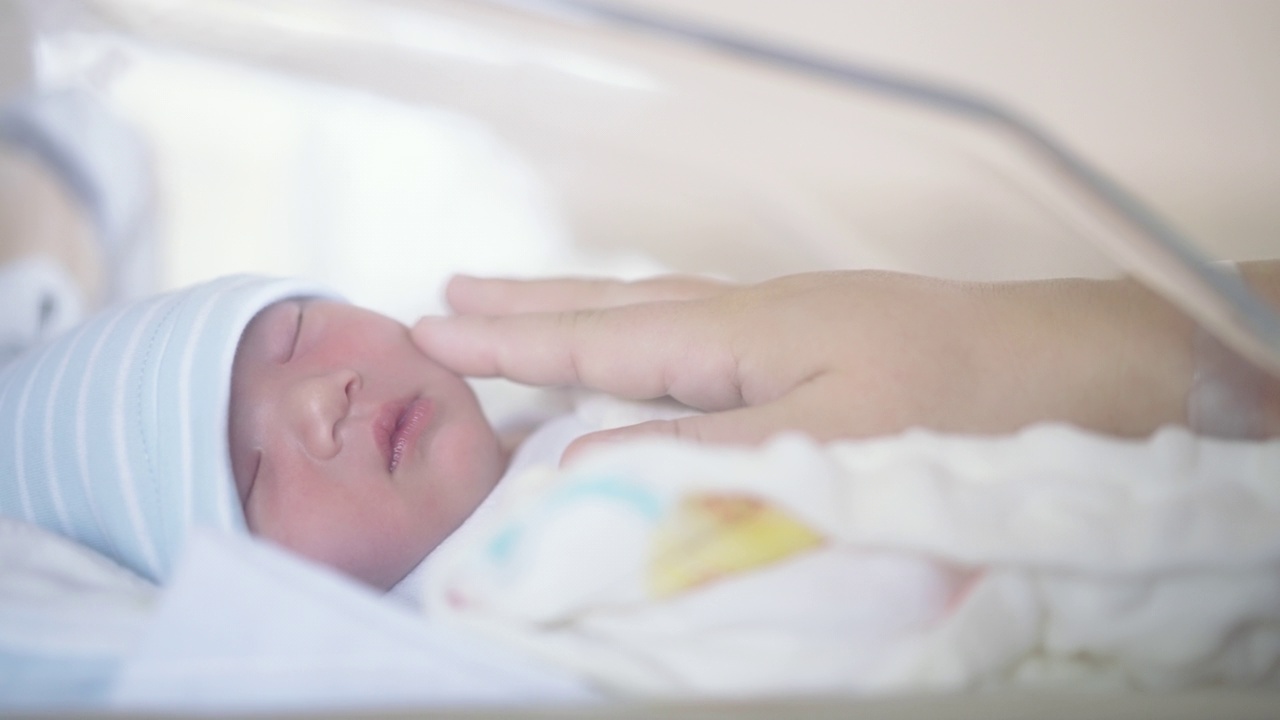 分娩后，母亲在医院充满爱地抚摸着刚出生的儿子视频素材