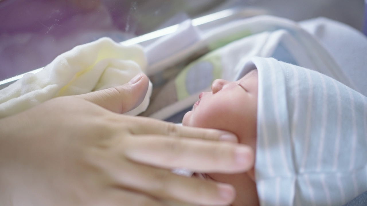 分娩后，母亲在医院充满爱地抚摸着刚出生的儿子视频素材