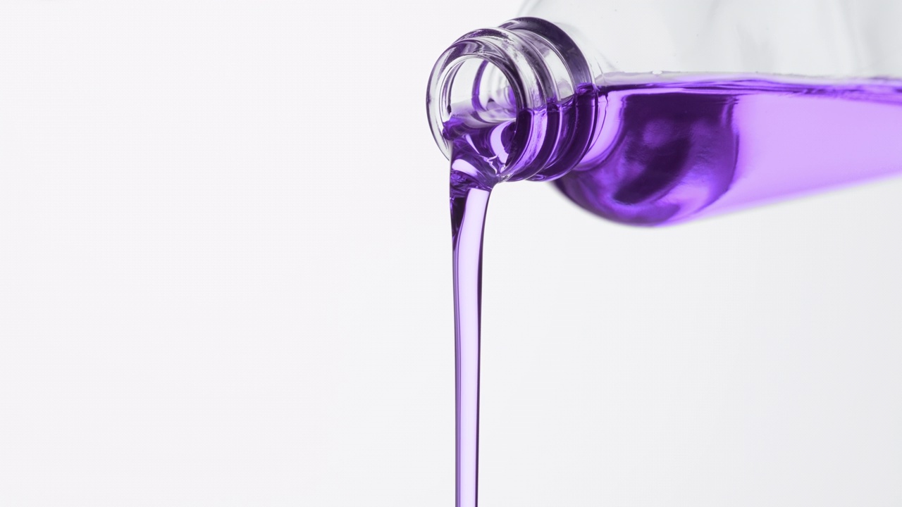 试剂瓶倾斜，紫色的油从瓶子里倾泻而出视频素材