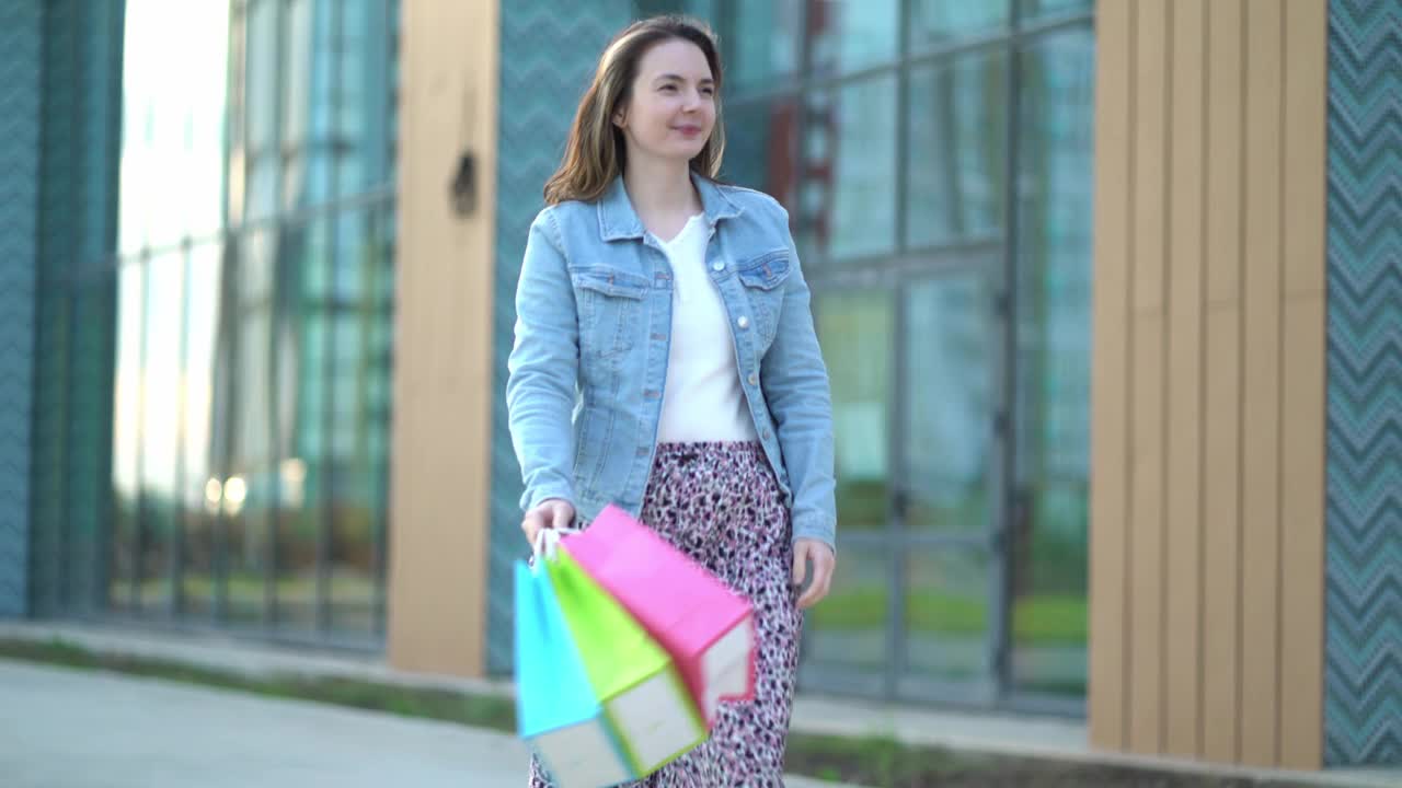 快乐满足的女人购物后。一个小女孩手里拿着不同颜色的袋子视频下载