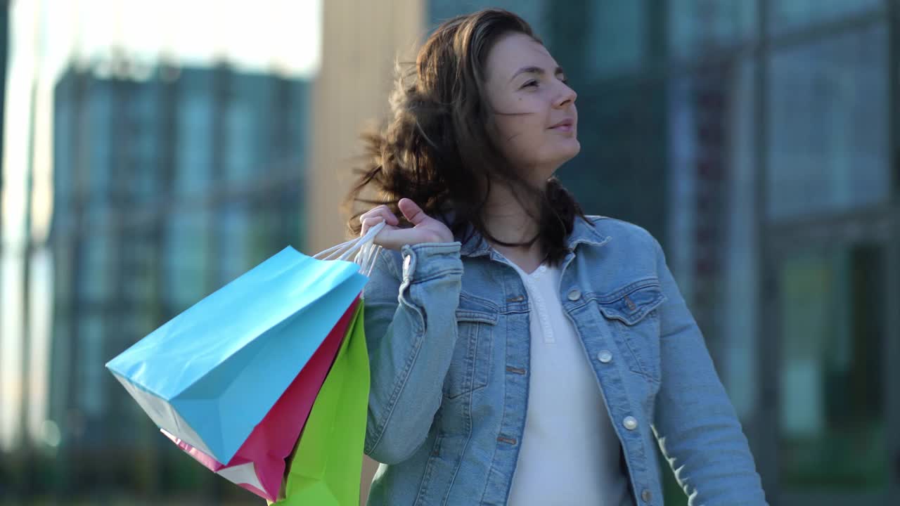 快乐满足的女人购物后。一个小女孩手里拿着不同颜色的袋子视频下载