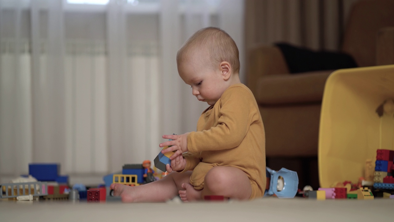 小男孩在家里房间的地板上玩五颜六色的积木。视频下载