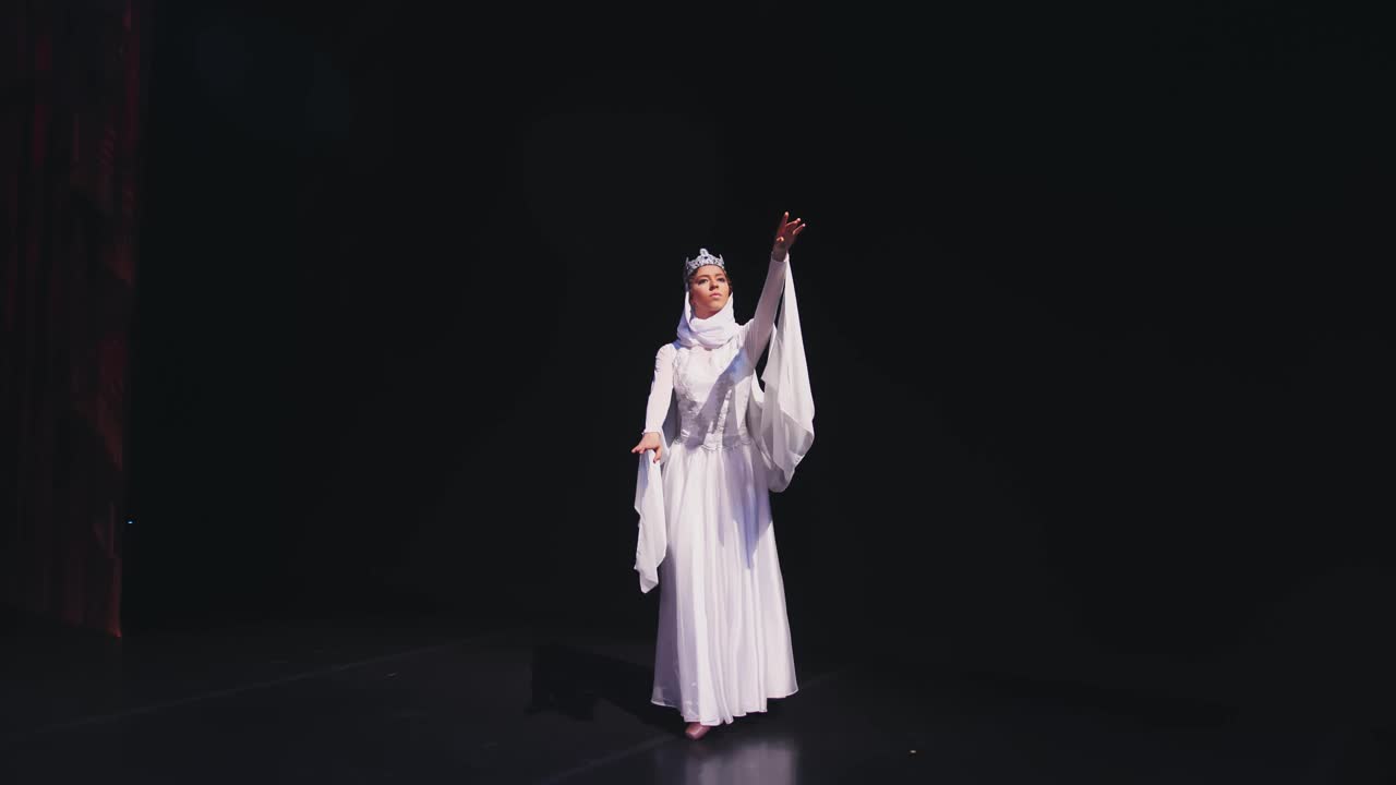 芭蕾舞演员走上舞台。一位芭蕾舞演员穿着美丽的白色长袍在黑色背景上跳舞。Raymonda变异。视频素材