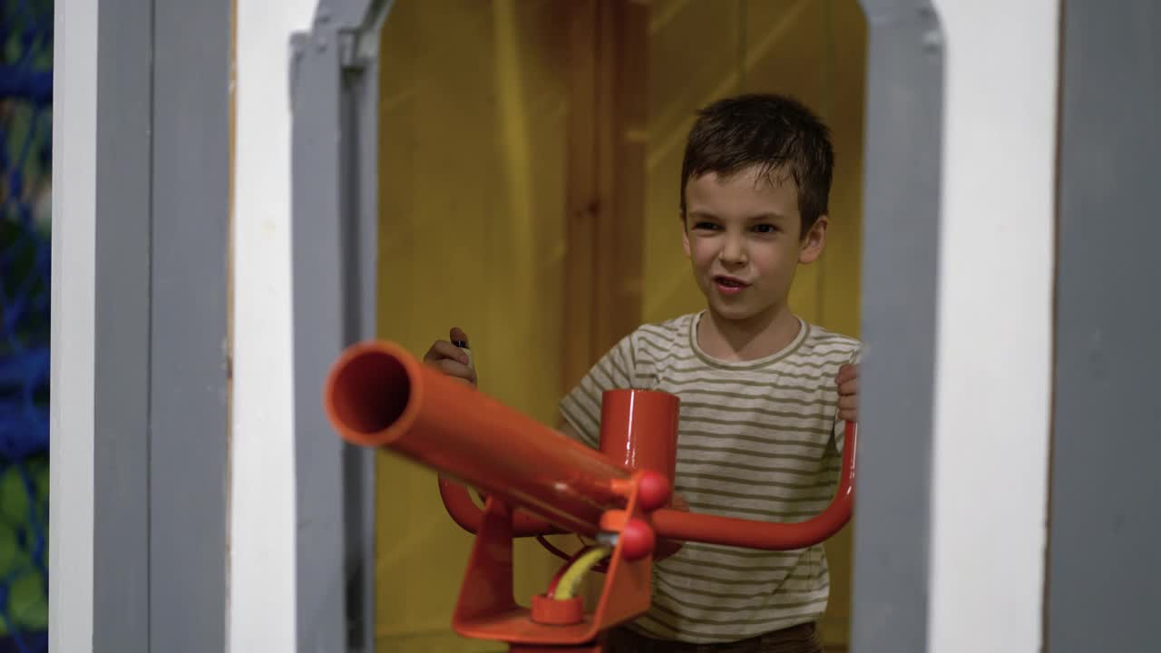 一个男孩在操场上用玩具充气大炮射击软球。视频下载