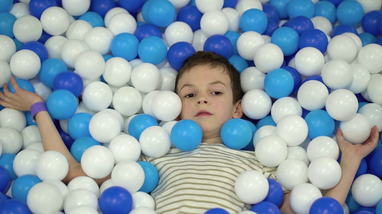 男生躺在游泳池里玩塑料球，在操场上玩。视频下载