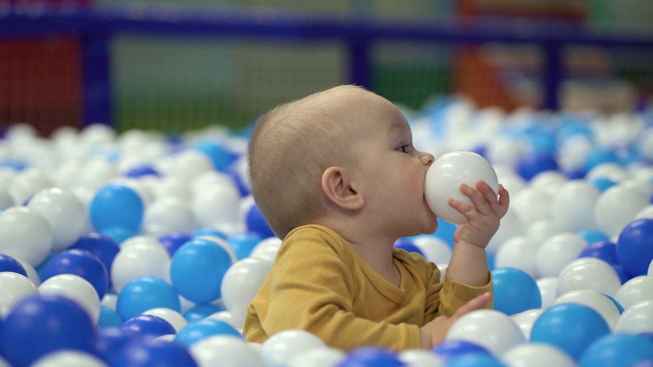 一个小男孩在操场上玩塑料球。视频下载