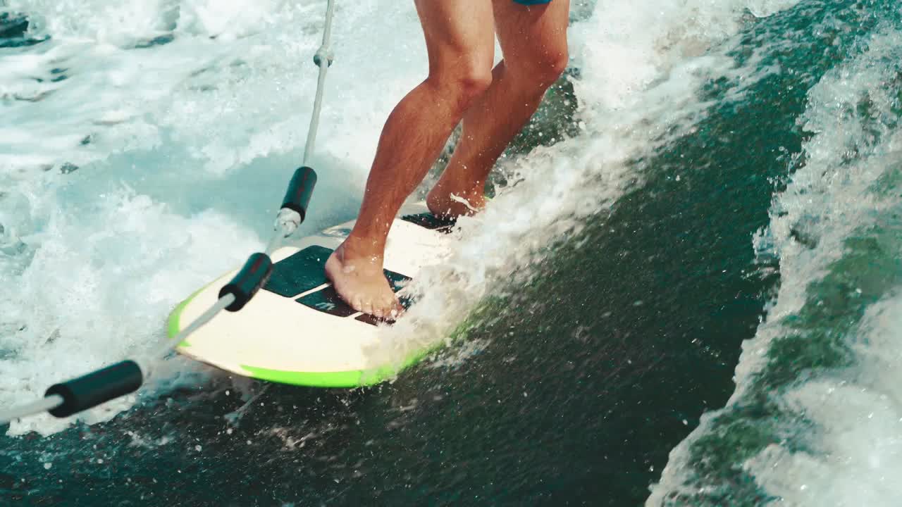 Wakesurfing。一个男子腿的冲浪板特写。花样，水上骑行。水上运动。夏天，色彩鲜艳。4 k视频下载