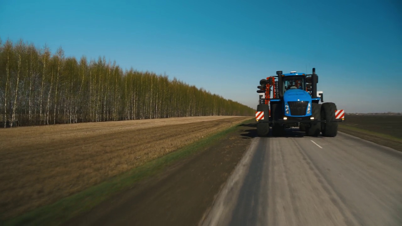 一辆巨大的蓝色拖拉机正驶往准备土壤的田地。Agroindustry。拖拉机的前视图。水平全景。农业机械4K视频下载