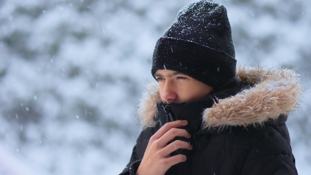 肖像年轻的冻结男孩站在森林地区在寒冷的一天，大雪旋风视频下载