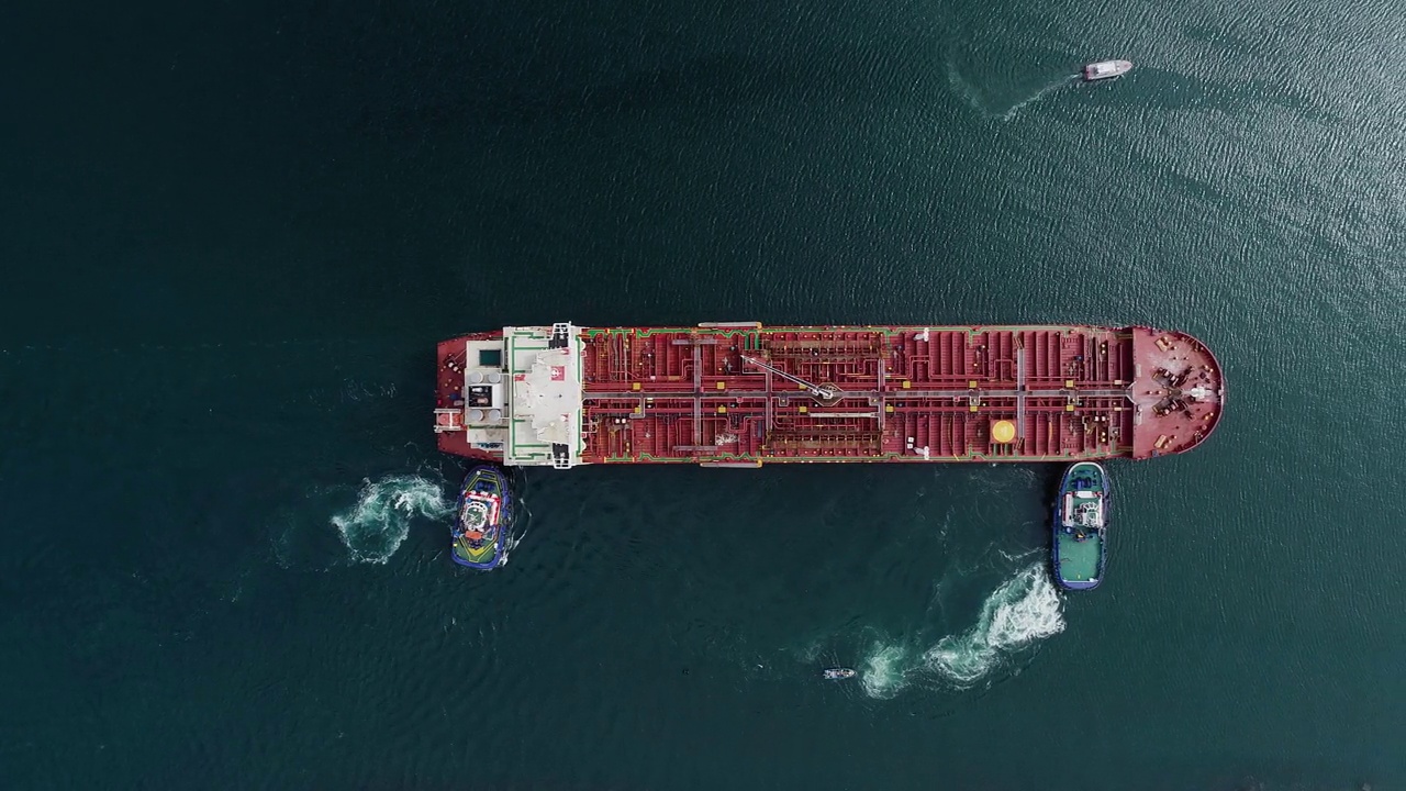 鸟瞰图上的船只推着一艘空货船，朝着港口-自上而下，无人机拍摄视频素材