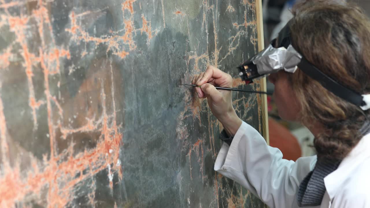 艺术修复师正在修复一幅上世纪的旧画，这幅画已经在圣所抽屉里被严重折叠了几十年视频下载