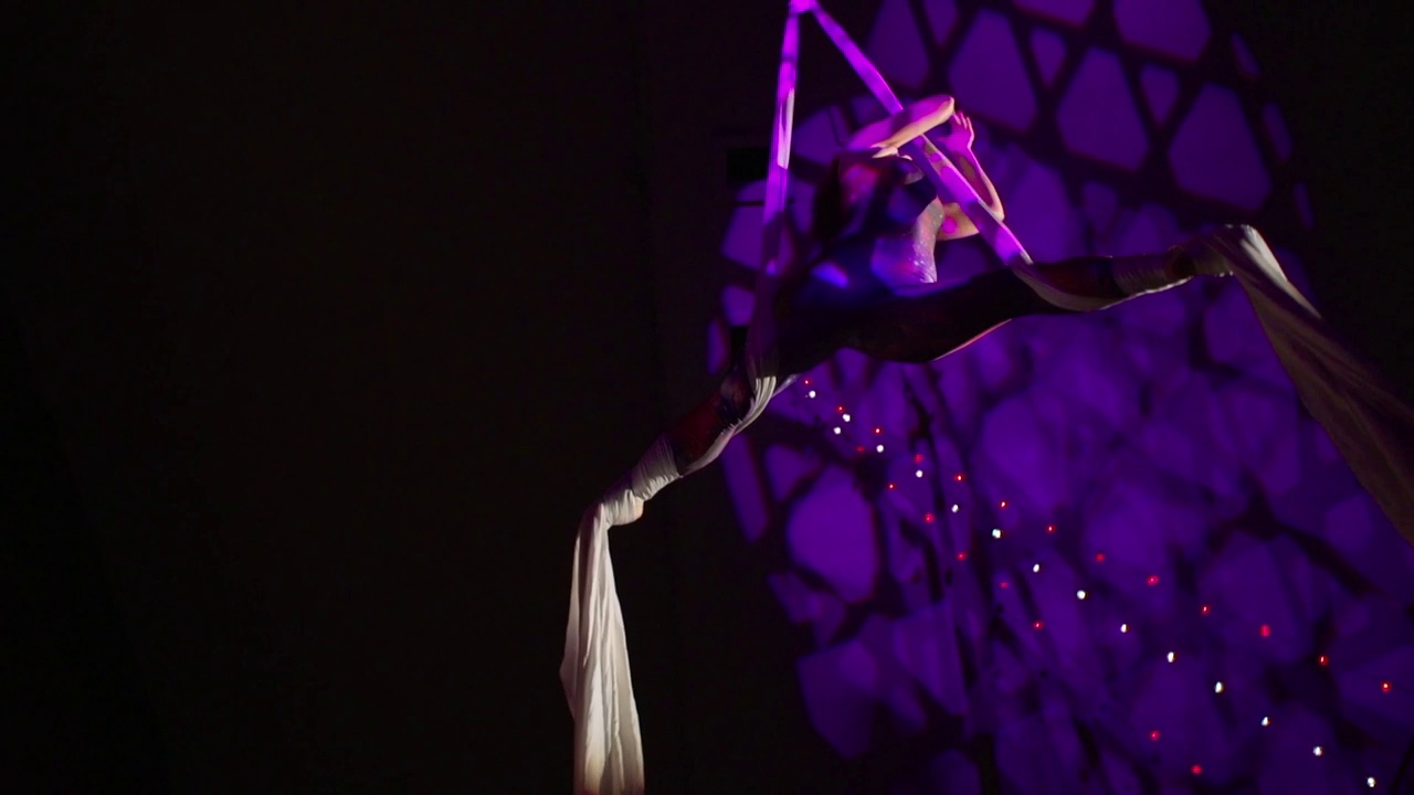 紫色灯光下，一个敏捷的空中丝绸表演者的美丽表演视频下载