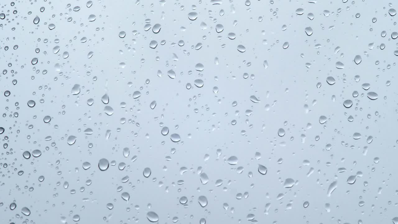 雨点在灰色的背景上顺着玻璃流下来。忧郁和无聊视频素材