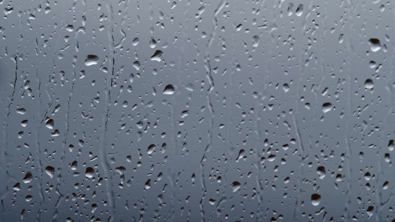 雨点在灰色的背景上顺着玻璃流下来视频素材