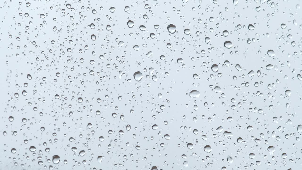 雨滴在明亮的背景上顺着玻璃流下来视频素材