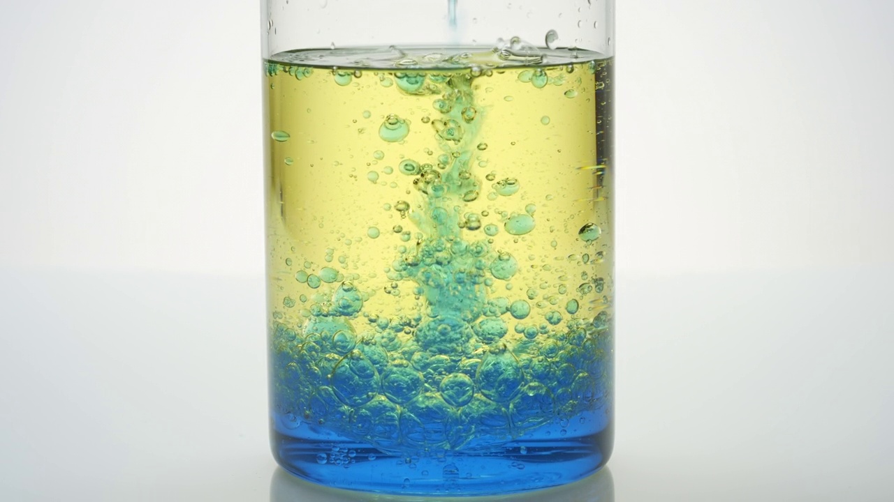 蓝色的油被倒入烧杯与蓝色和黄色的油视频素材