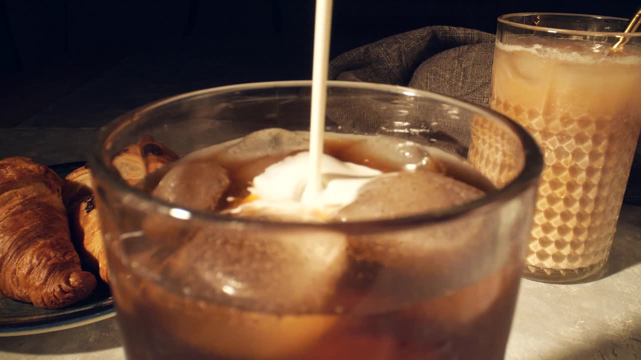 清凉的夏日饮品概念。将奶油倒入杯中，杯底是灰色的冰咖啡视频素材