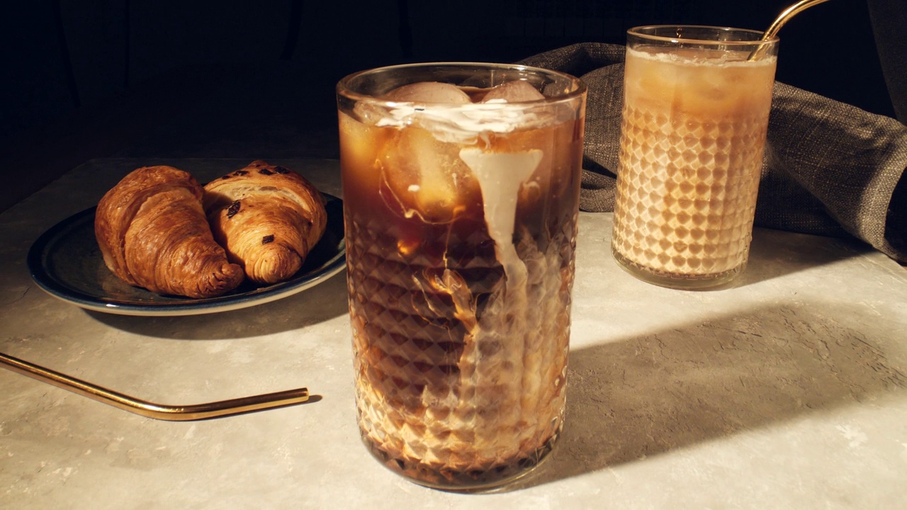 清凉的夏日饮品概念。将奶油倒入杯中，杯底是灰色的冰咖啡视频素材