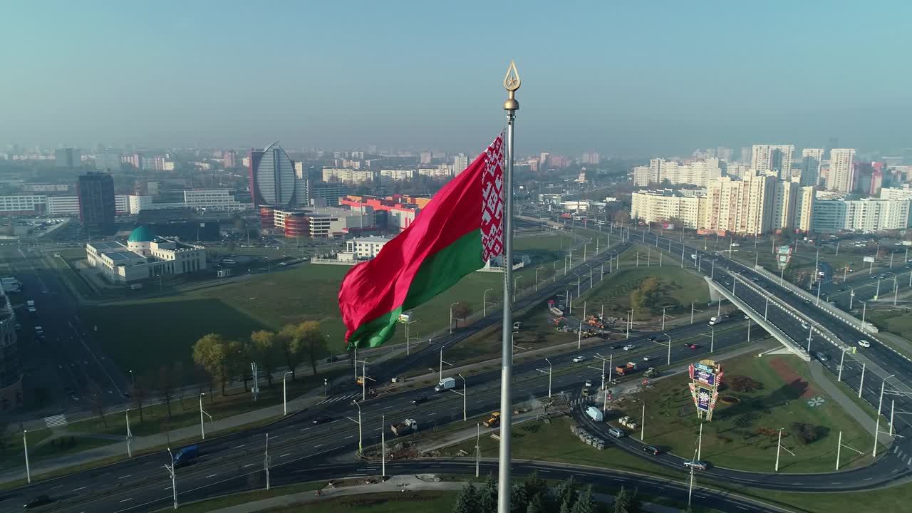 在一个阳光明媚的早晨，白俄罗斯国旗飘扬在蓝天和明斯克的城市景观上视频下载