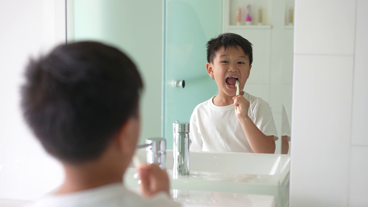 亚洲小孩在白色干净的浴室里刷牙。日常健康和牙齿护理的概念视频下载
