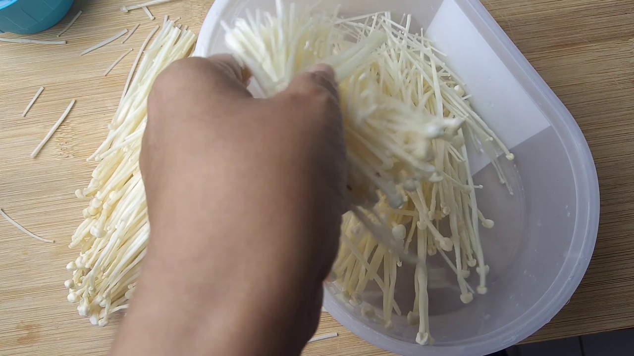 将新鲜的金针菇放入塑料碗的镜头视频下载