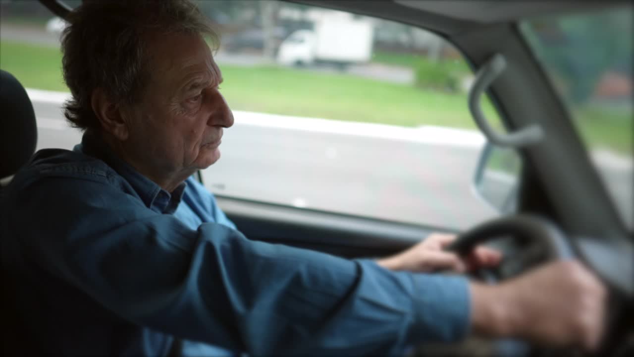 资深的驾驶在移动车辆内。老人握着汽车方向盘在路上行驶。人旅行视频下载