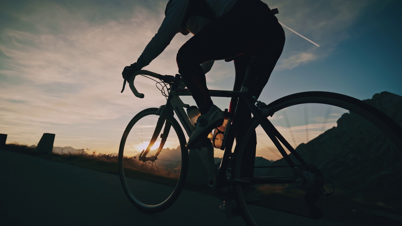 骑自行车的人在日出山的道路上坡视频下载