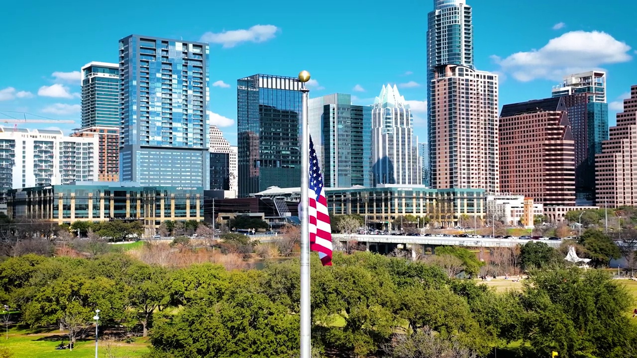 美国国旗在德克萨斯州奥斯汀市景前飘扬视频下载