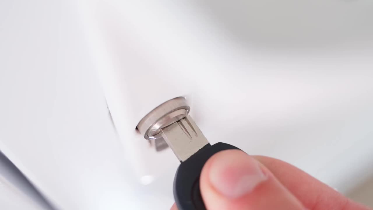 一只手在白色塑料门的钥匙孔里转动钥匙，然后把钥匙从锁里拔了出来。视频素材