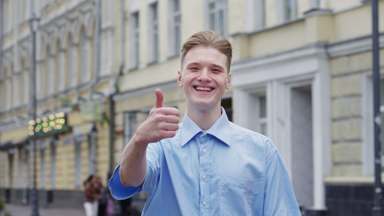 年轻的白人男子微笑着，自信地做得很好，在街上竖起大拇指视频素材