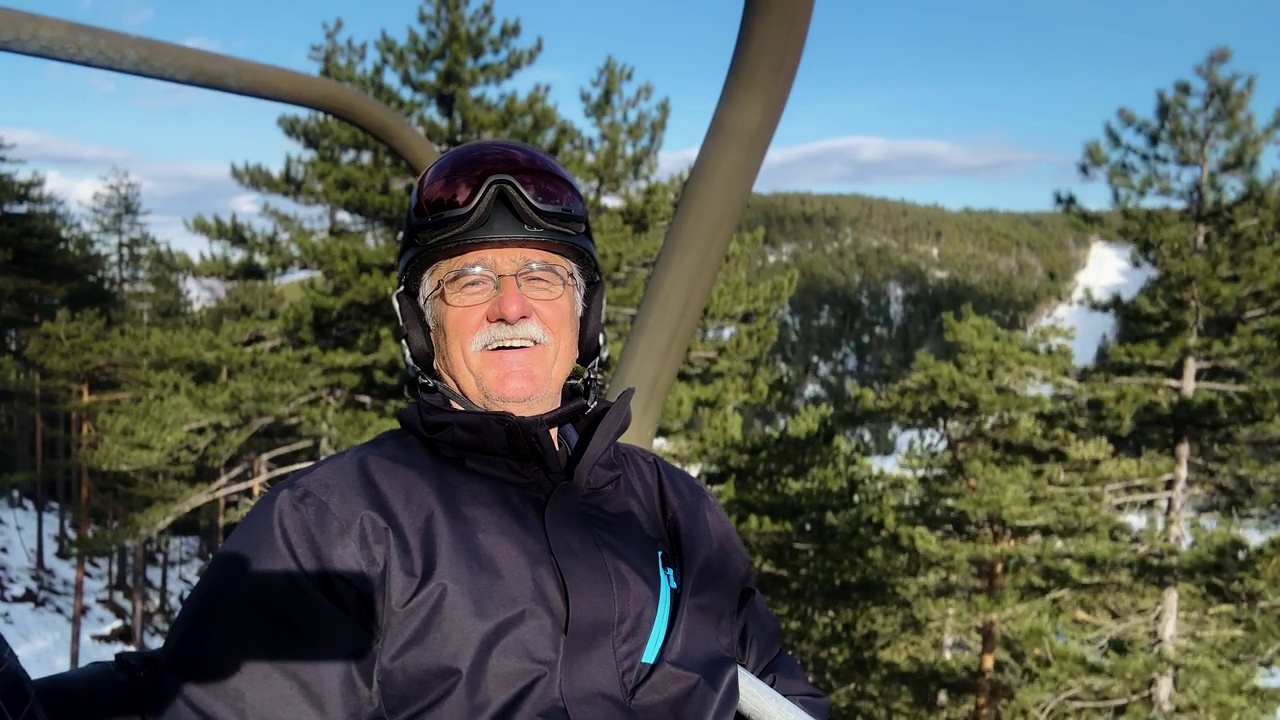 白人男子的肖像，穿着滑雪服骑在滑雪缆车上视频下载