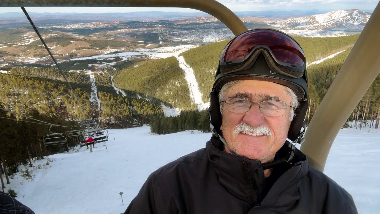 白人年长的男子的肖像，穿着滑雪服骑在滑雪缆车上视频下载