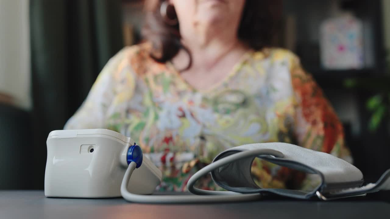 年长的退休妇女在家里用数字测量设备4k库存视频检查血压视频下载