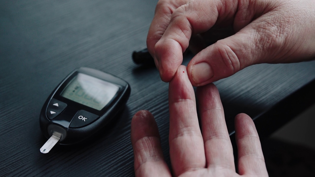 老年妇女采取样本血糖与糖尿病使用血糖仪在家里测试血糖4k股票视频视频下载
