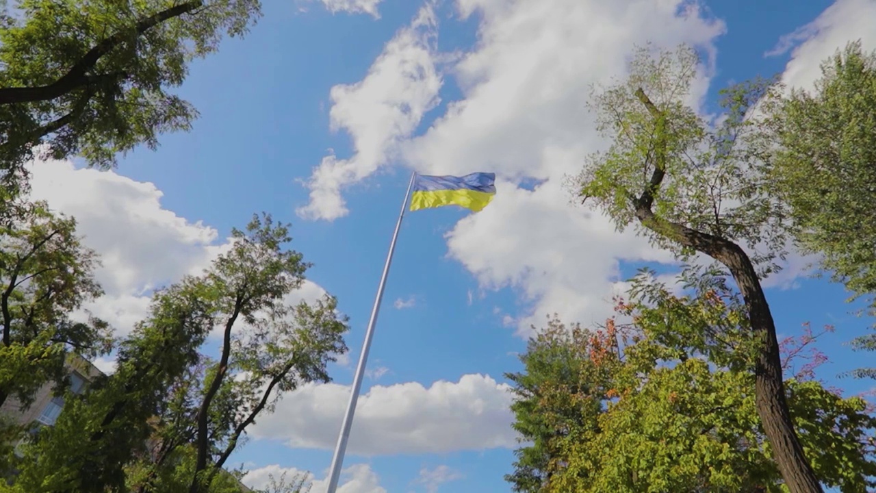 缓慢移动的旗杆上的乌克兰国旗。乌克兰国旗在风中飘扬的慢镜头。视频下载
