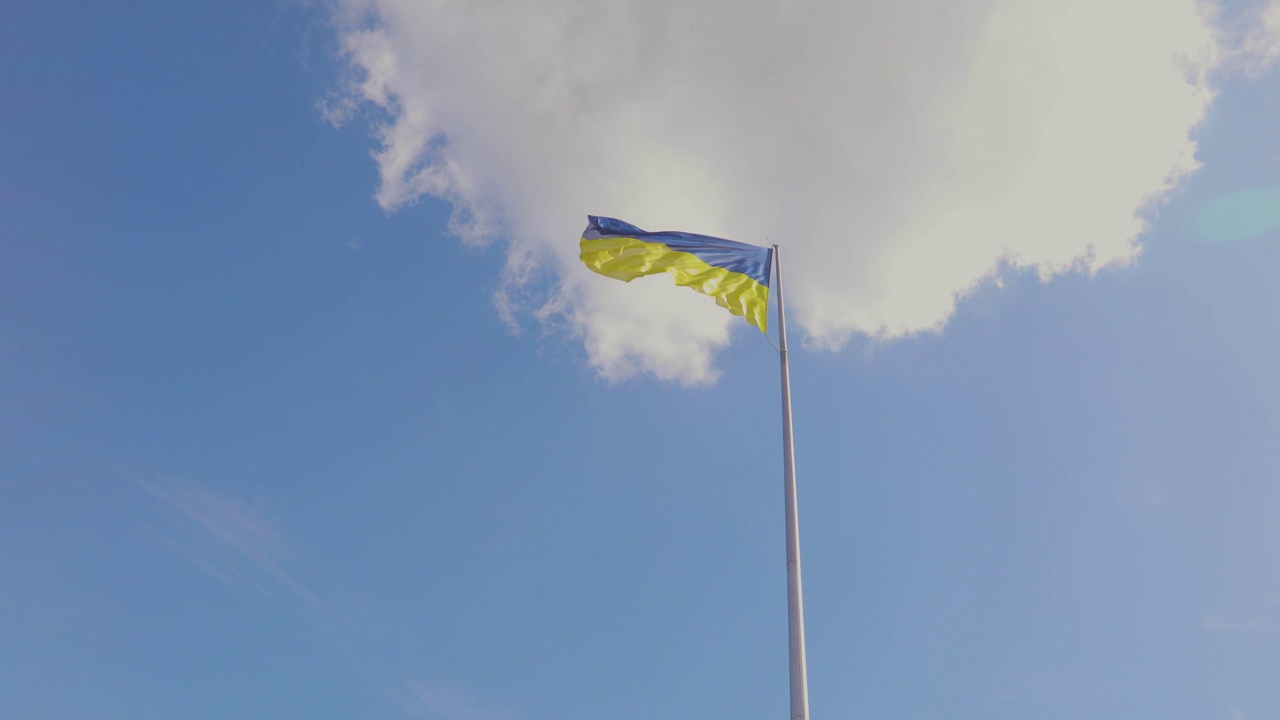 风中飘着乌克兰果国旗。乌克兰国旗迎风飘扬。乌克兰国旗映衬着天空视频下载