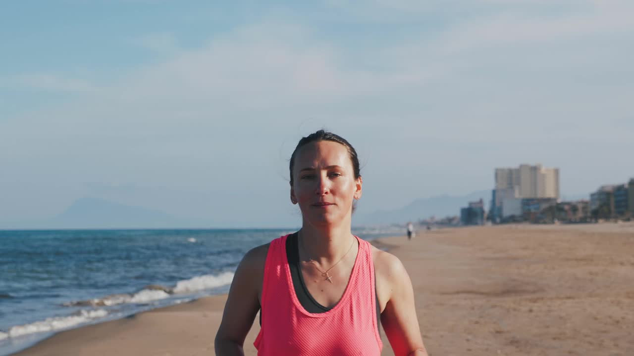 年轻健康的女人，肌肉发达的身体，早上沿着沙滩跑步视频下载