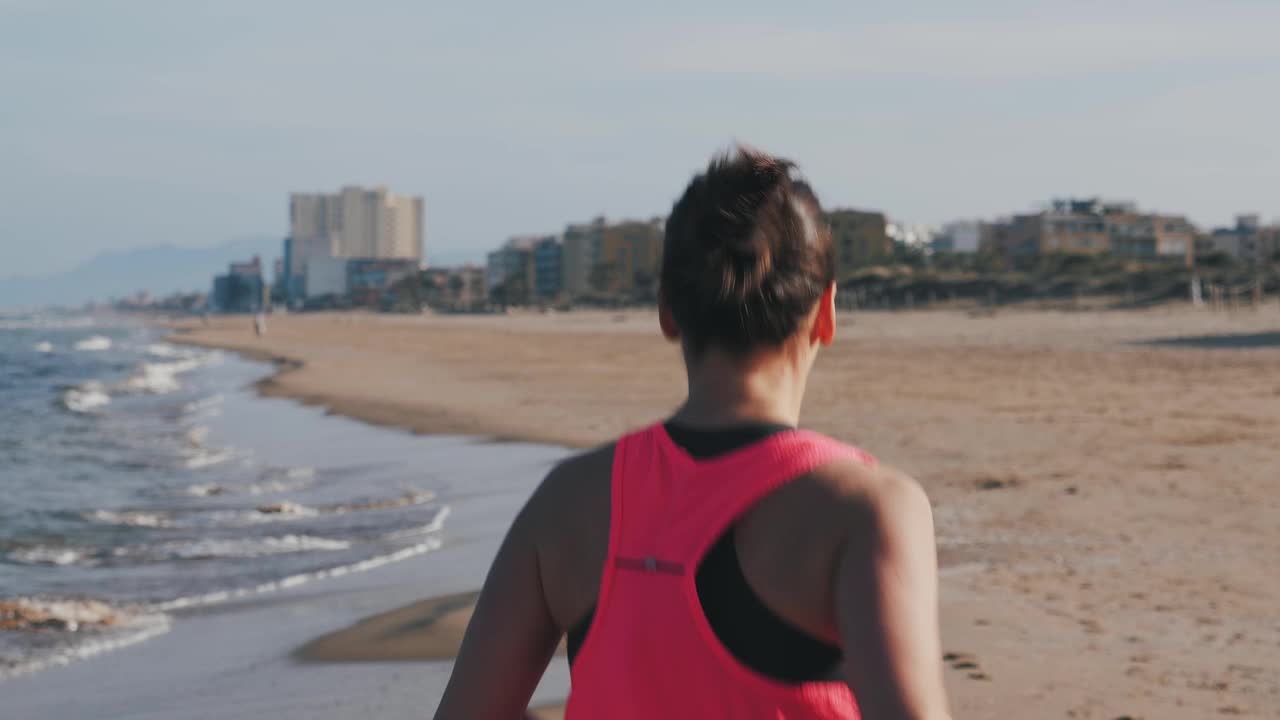 强壮的女人在沙滩上奔跑。积极运动的女性在户外锻炼视频下载