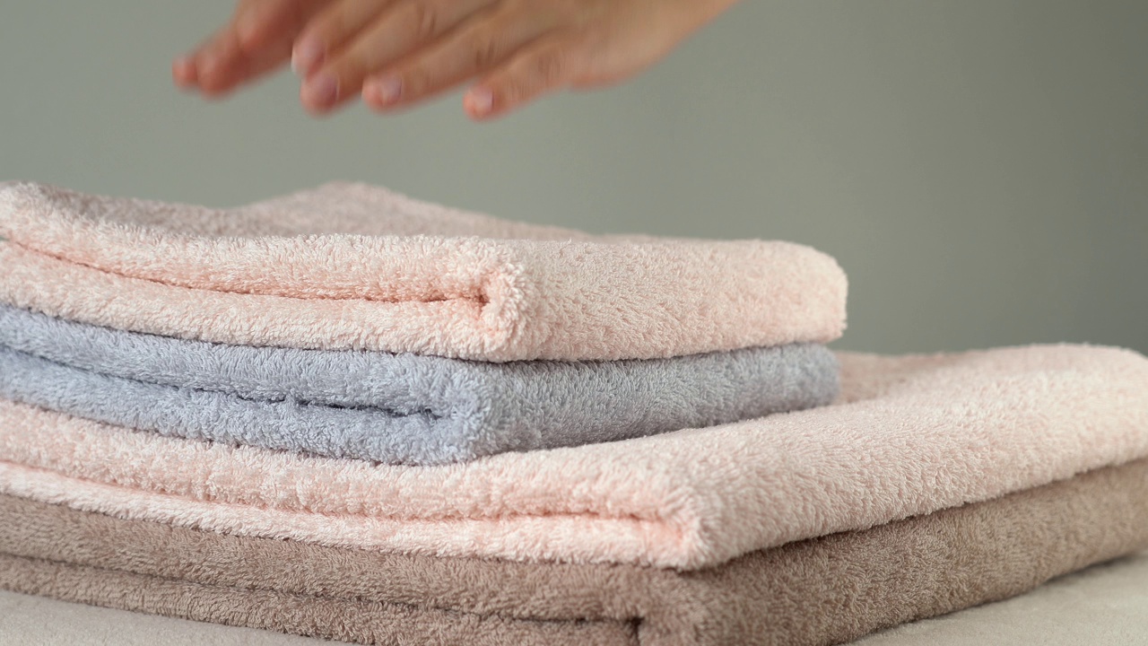 女性用手调整叠好的毛巾。洗澡,洗衣服。家庭、酒店、水疗中心视频素材