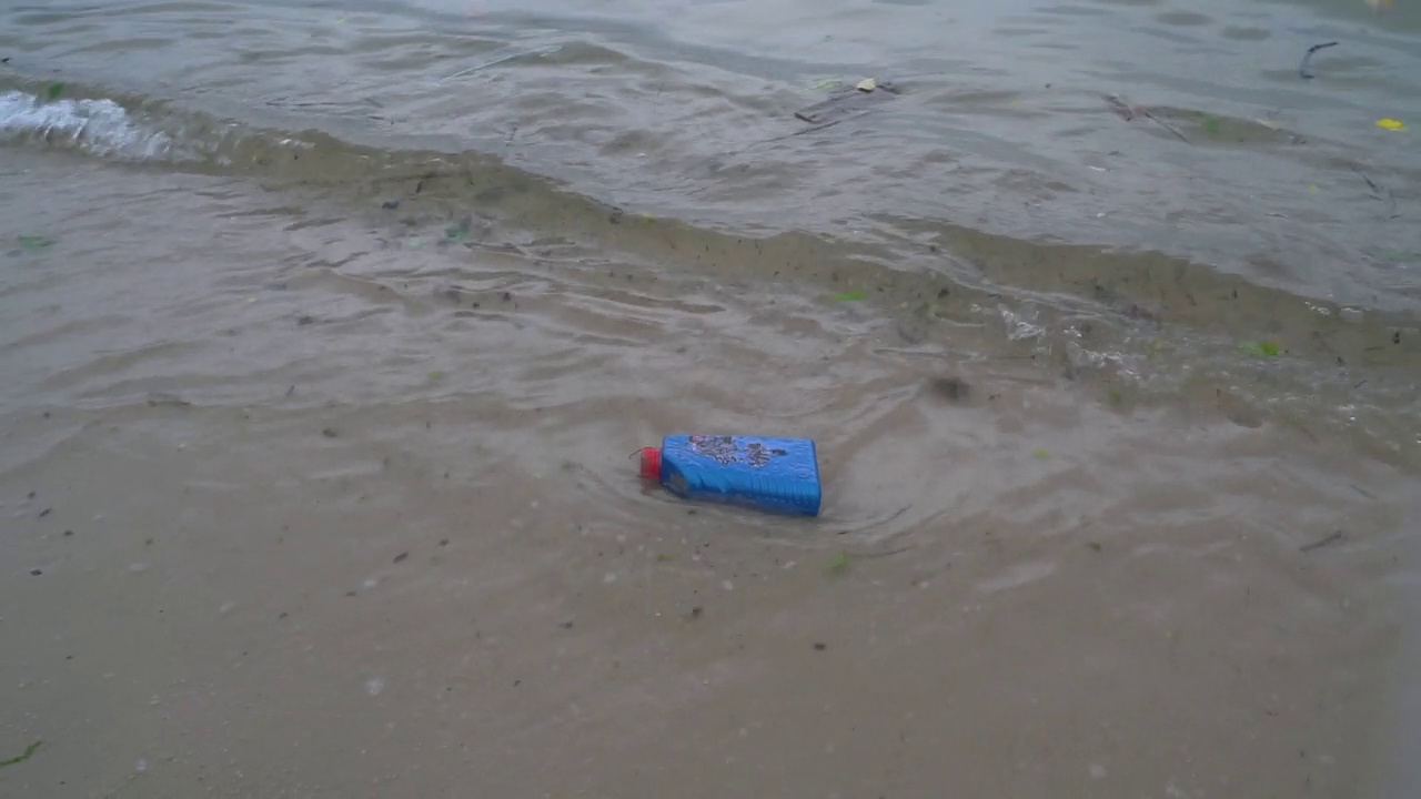 蓝色的塑料瓶子漂浮在海滩上视频下载