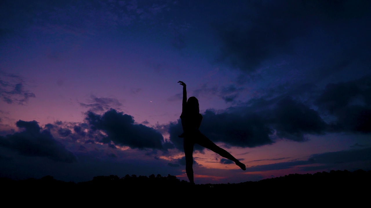 一个女人在日落时在湖上跳舞的剪影视频下载