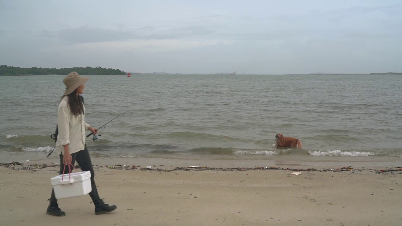 一名亚裔中国妇女带着她的狗在海滩上钓鱼视频下载